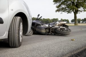 Motorcycle on the road in front of car after a collision