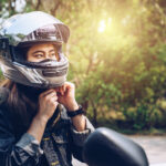 Confidence Asian woman wearing a motorcycle helmet before riding. Helmets contribute to motorcycle safety by protecting the rider's head.