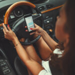Woman is texting on smartphone while driving a car and leads herself to danger.